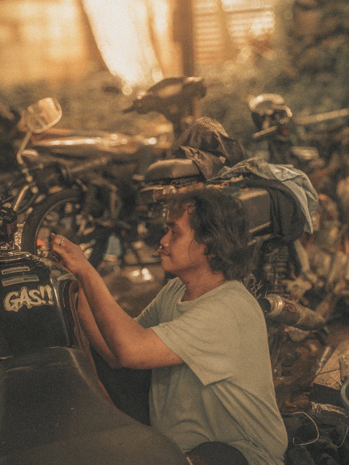 creative-03 Mechanic working on a motorcycle in a rustic Indonesian workshop, warm light.